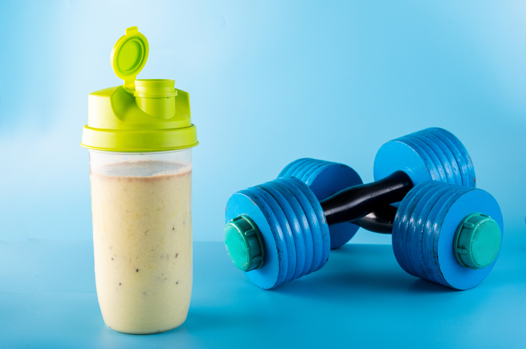 Sports shaker with sports nutrition. Protein shaker. Dumbbells.